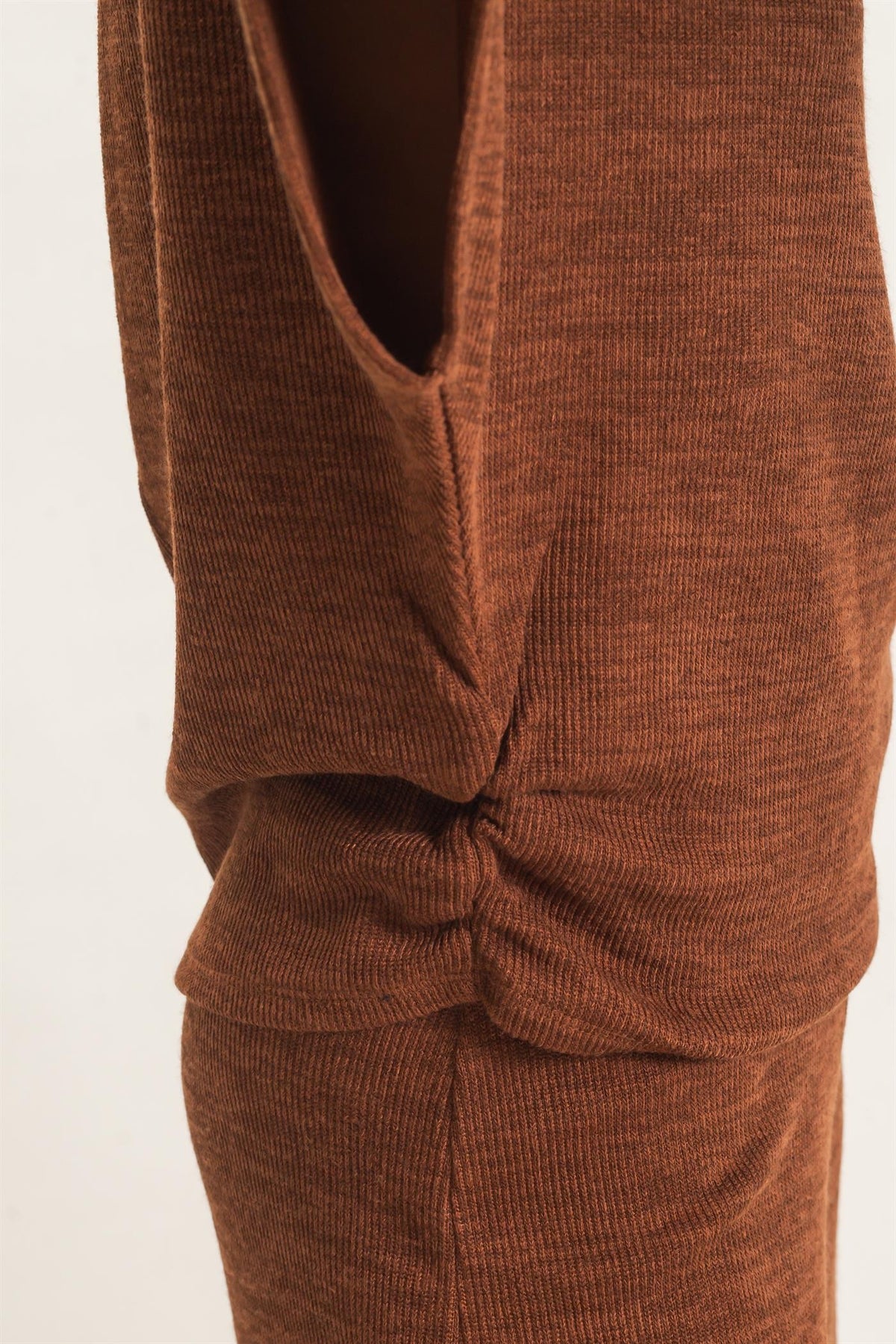 Close-up of a brown ribbed knit garment with a twisted knot detail at the waist, shown against a plain light background.