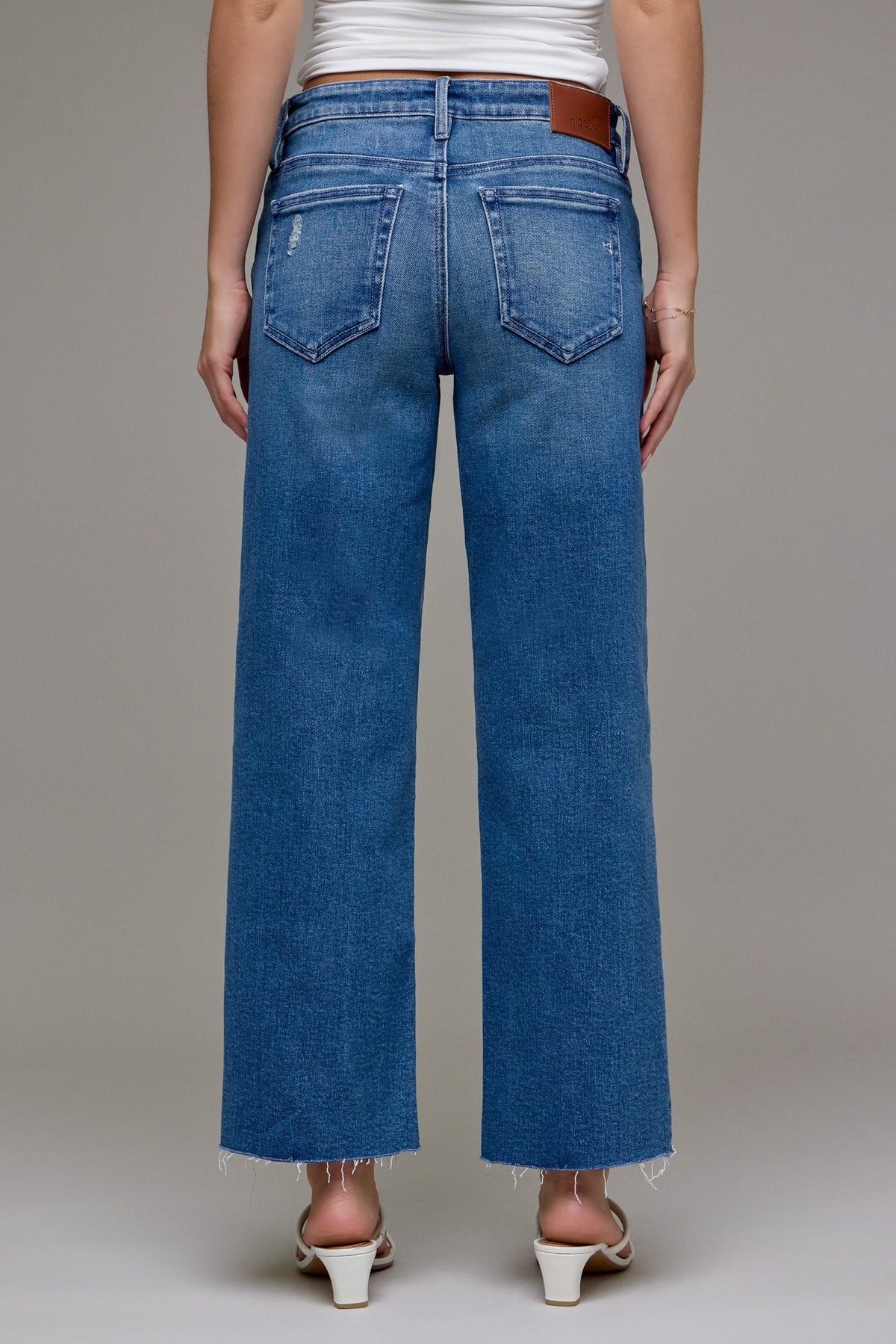 Person wearing cropped classic straight leg blue jeans on a plain background