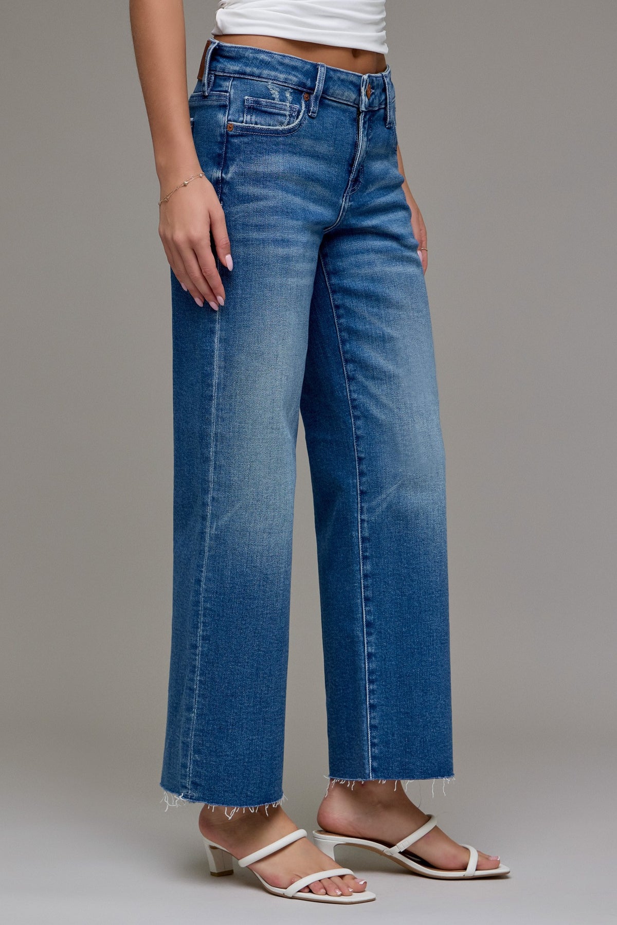 Person wearing cropped classic straight leg blue jeans on a plain background