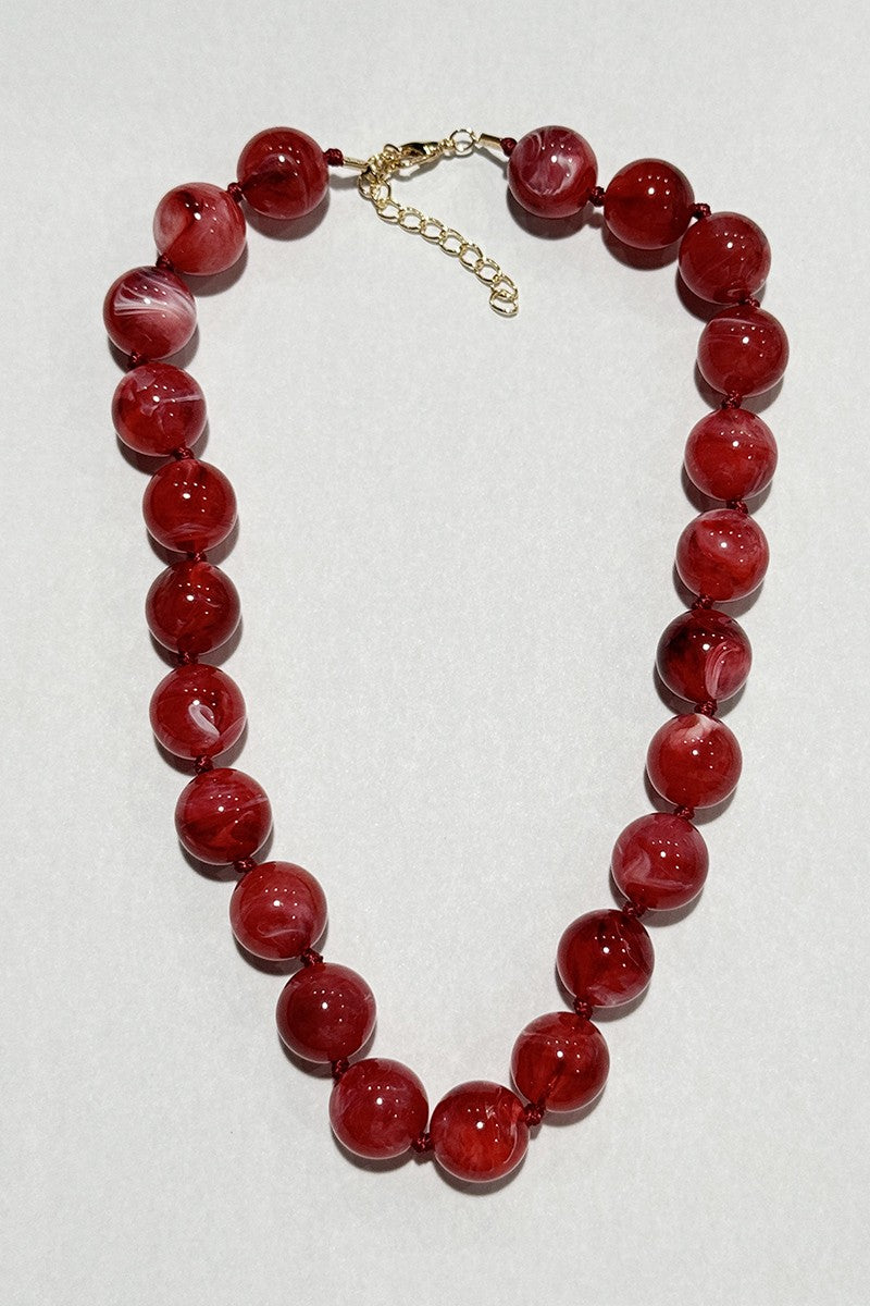 Red beaded necklace on a white background