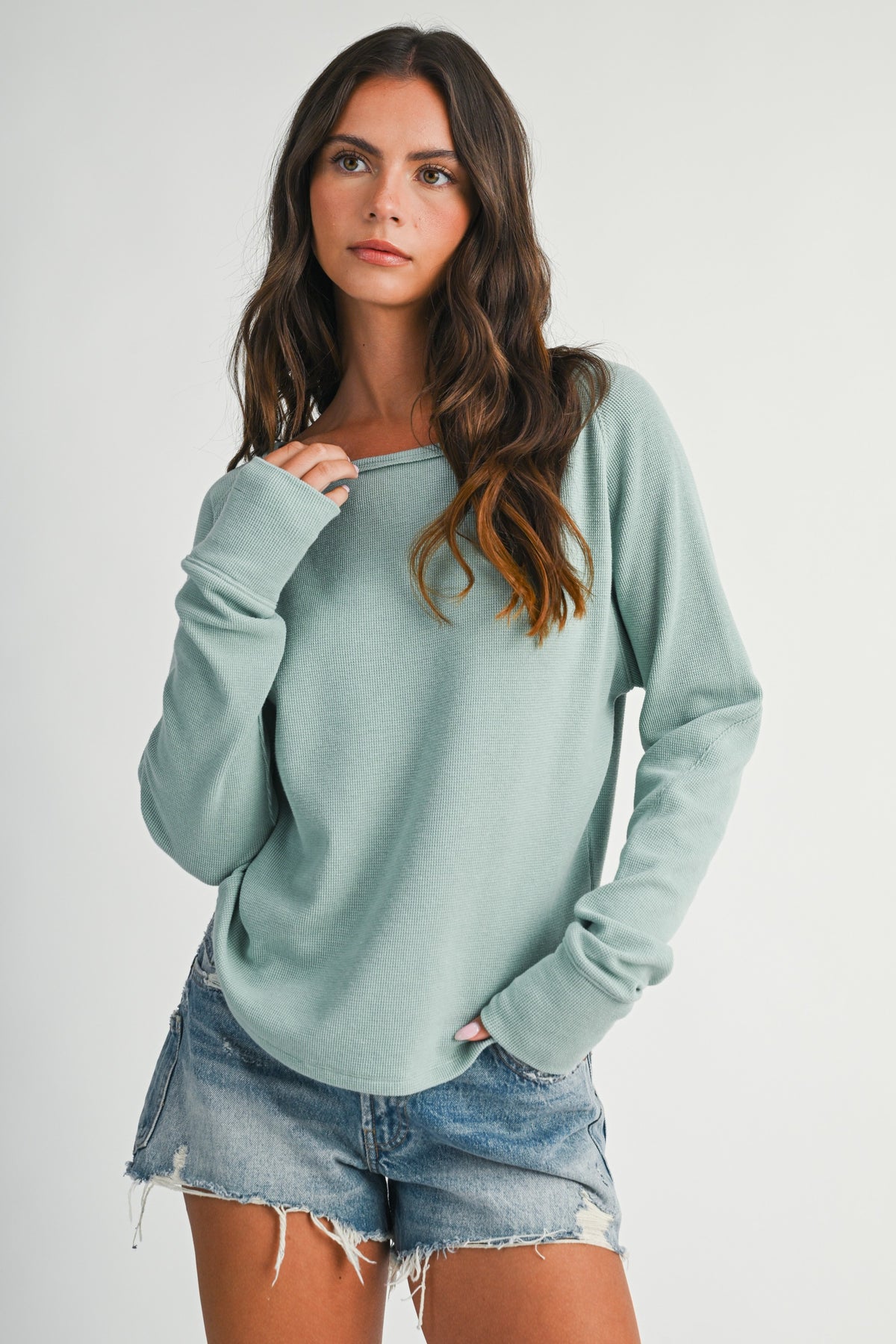 Women wearing an aqua blue thermal kni long sleeve top and denim shorts.