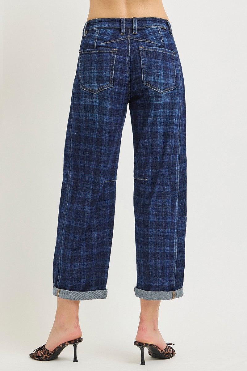 Back view of a person wearing blue plaid cropped jeans with rolled hems and black mule heels, photographed against a plain light background.