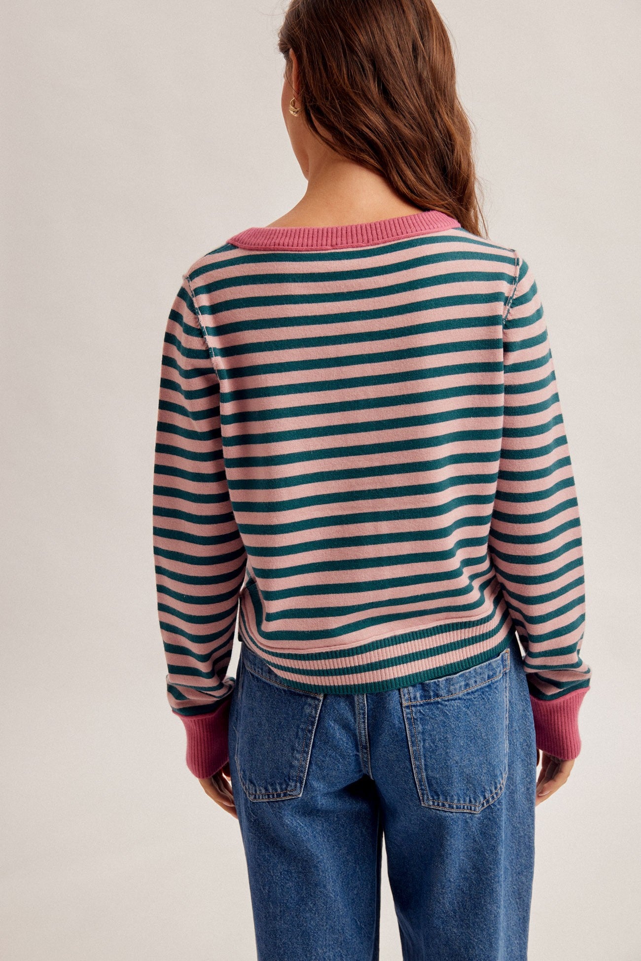 Women wearing a stripe button down cardigan in forest green/rose and denim jeans.