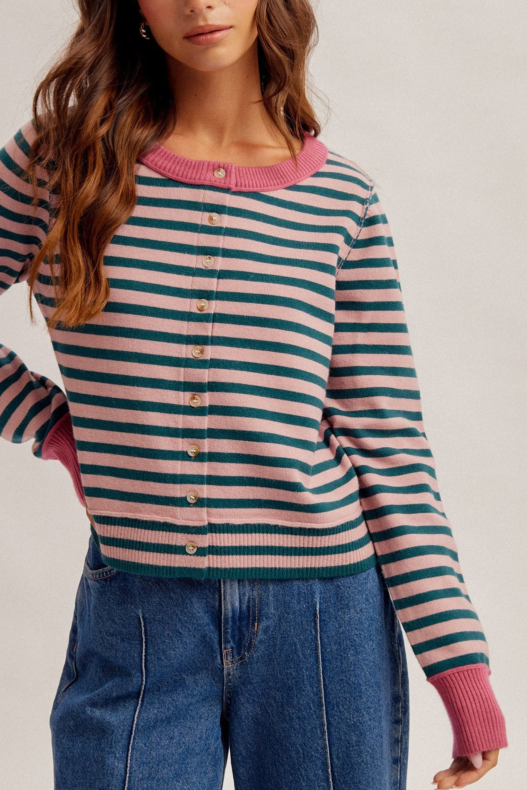 Women wearing a stripe button down cardigan in forest green/rose and denim jeans.