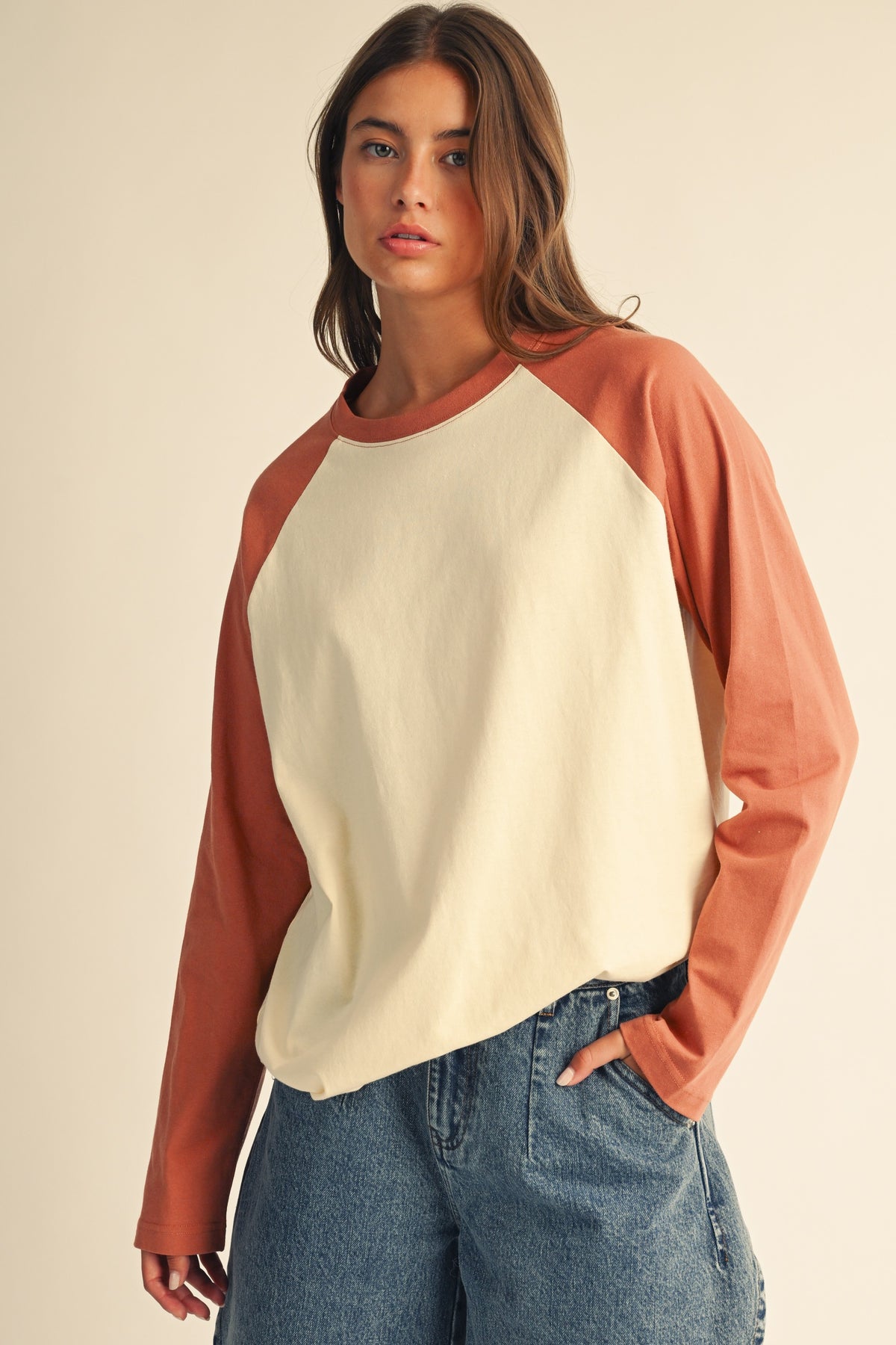 Women in a contrast raglan long sleeve baseball tee in butter terracotta and blue denim jean shorts.