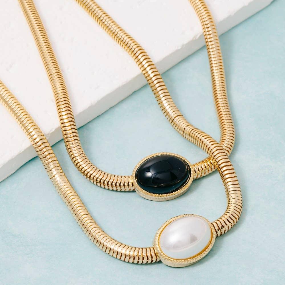 Gold necklace with a black stone on a gray background