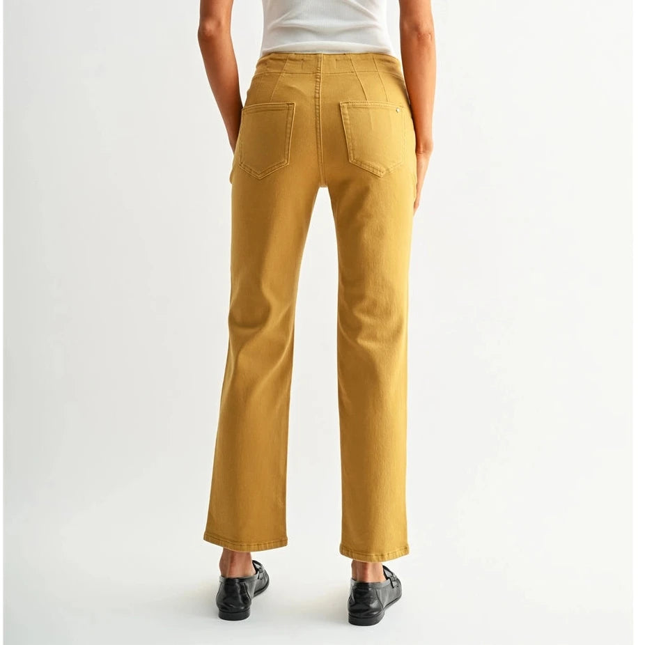 A woman viewed from behind wearing mustard yellow cropped flare pants, a white ribbed tank top, and black loafers against a light gray studio background.