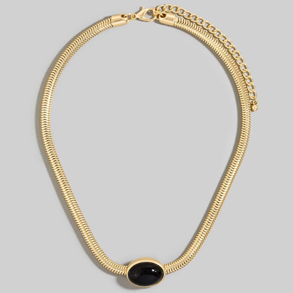 Gold necklace with a black stone on a gray background