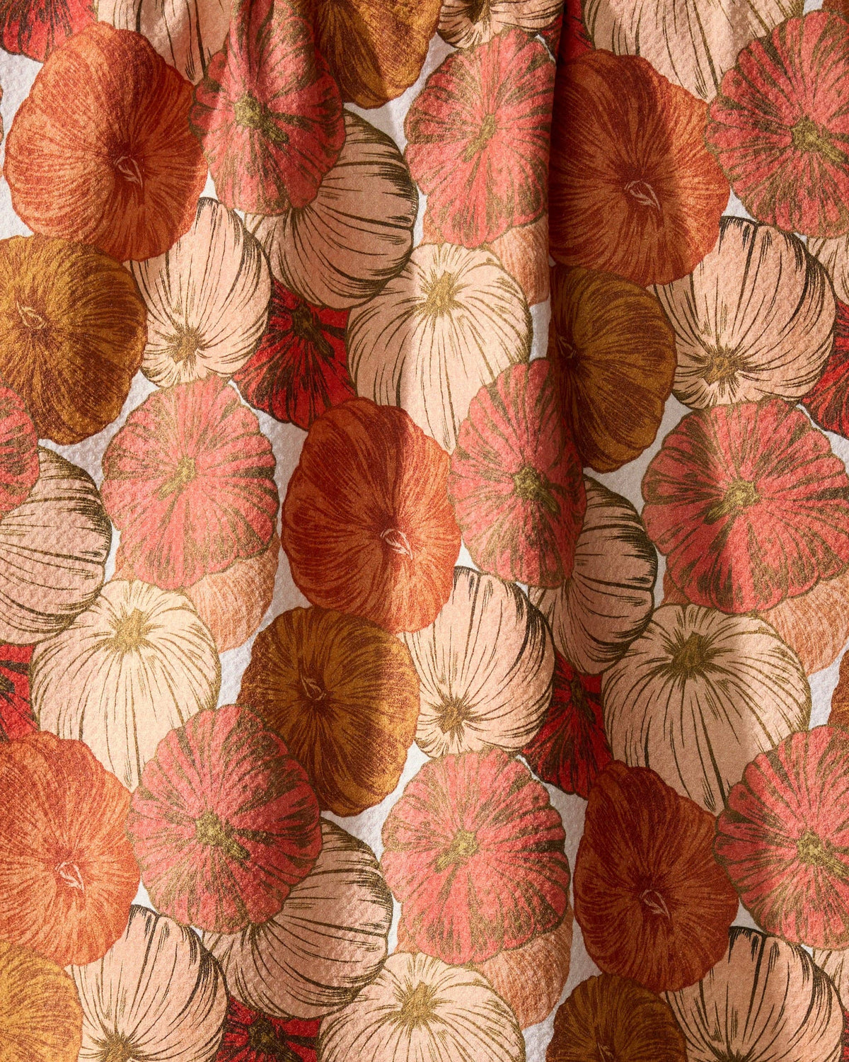 Patterned fabric with red, orange, and beige pumpkin design on a white background