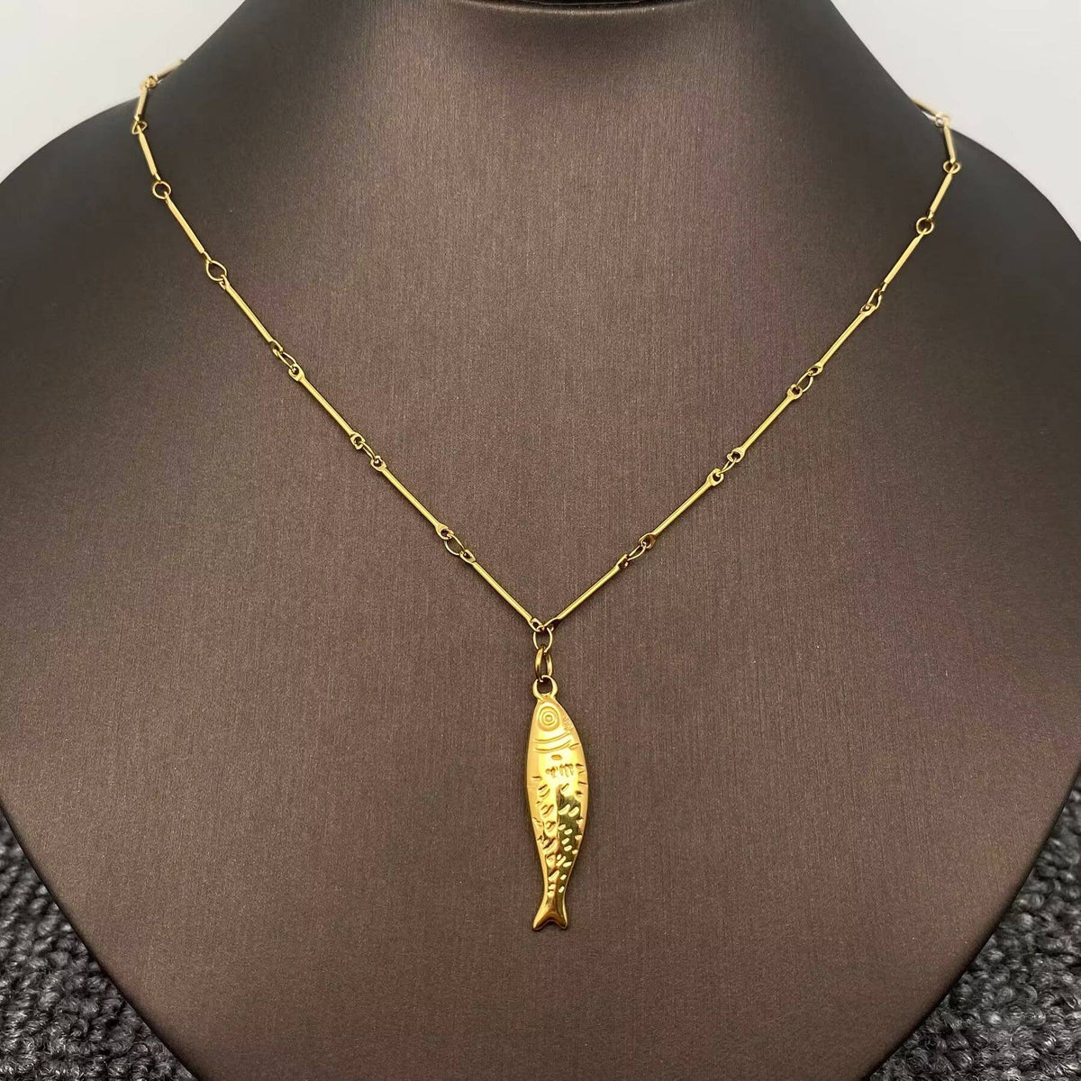 Gold fish pendant necklace on a mannequin neck