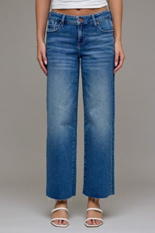 Cropped classic straight leg blue jeans worn by a person on a plain background