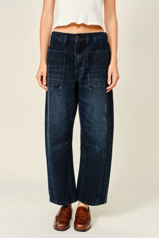 Women wearing dark washed barrel jeans and a white cropped top.
