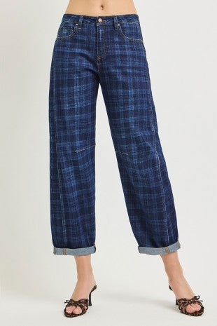 A person wearing dark blue plaid cropped jeans with rolled cuffs and brown heeled sandals, shown from the waist down against a light gray studio background.
