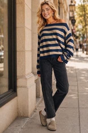 Women in a stripe boat neck sweater with jeans and slides.