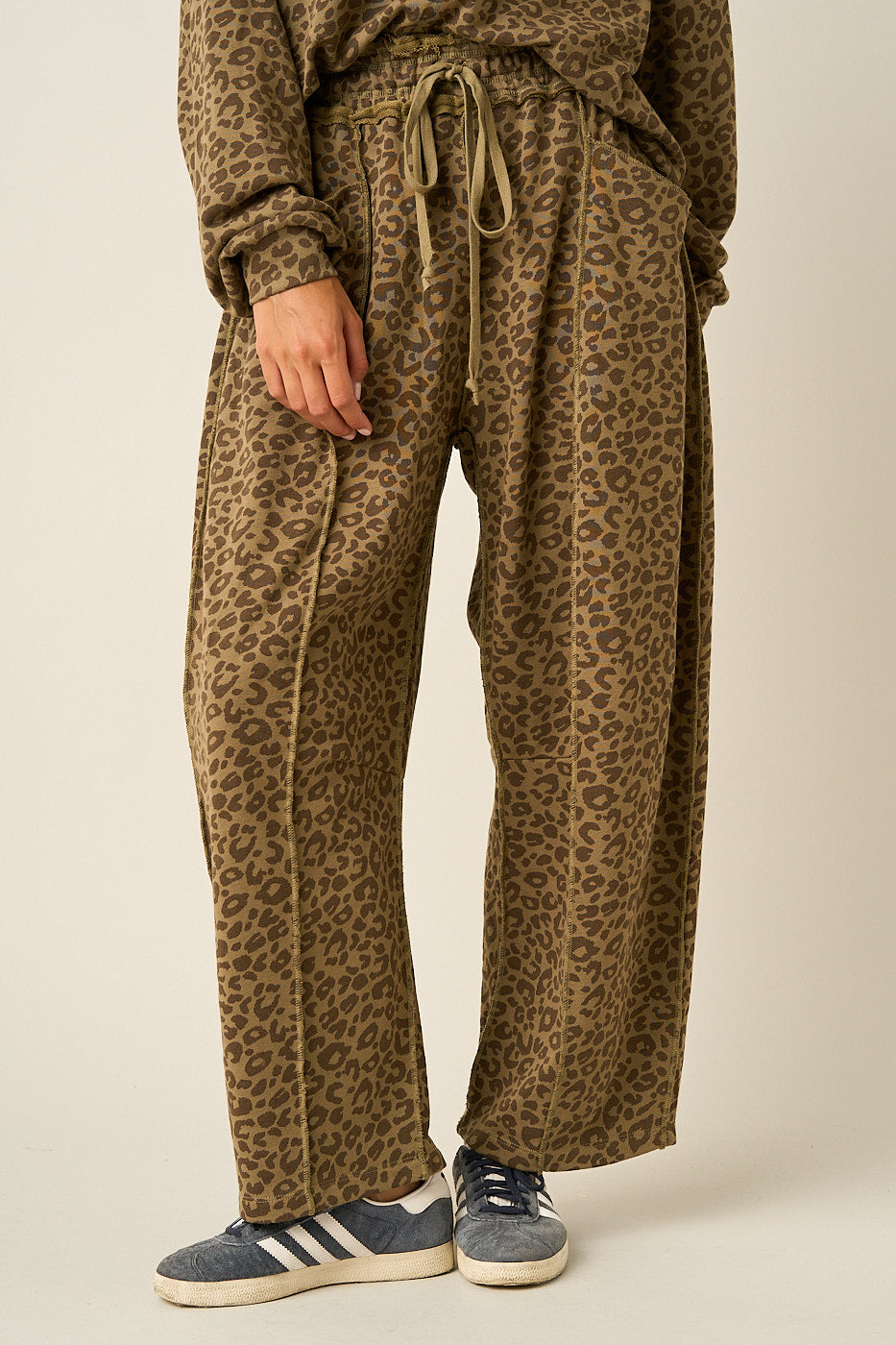 Women wearing leopard print barrel pants and matching top on a light background.