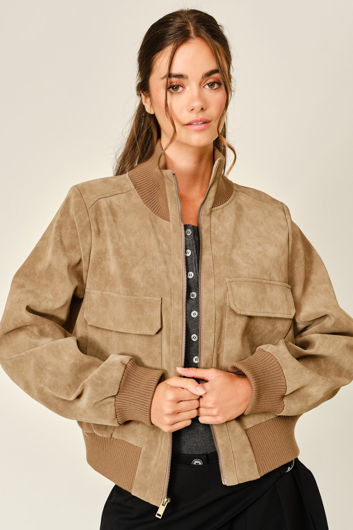 Women wearing a mocha colored suede jacket with a grey button down shirt and black pants.