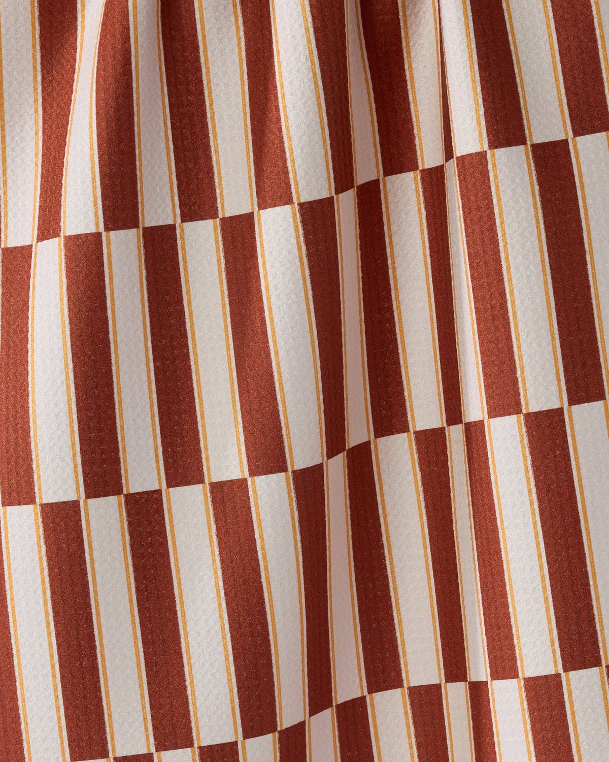 A close-up of a fabric pattern featuring alternating vertical stripes in terracotta red and off-white, separated by thin gold lines.