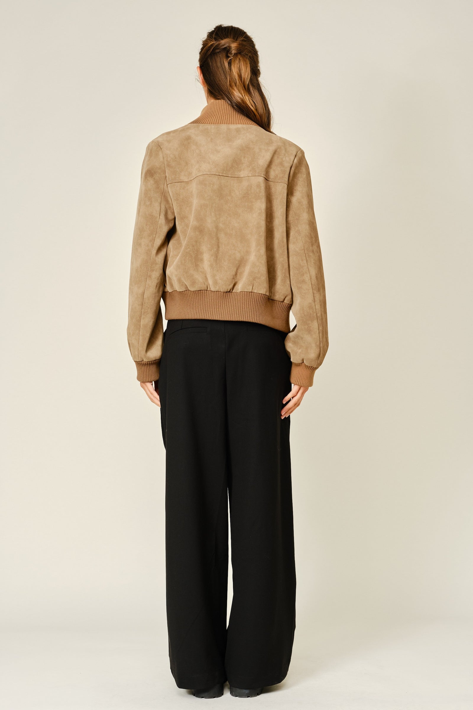 Women wearing a mocha colored suede jacket with a grey button down shirt and black pants.