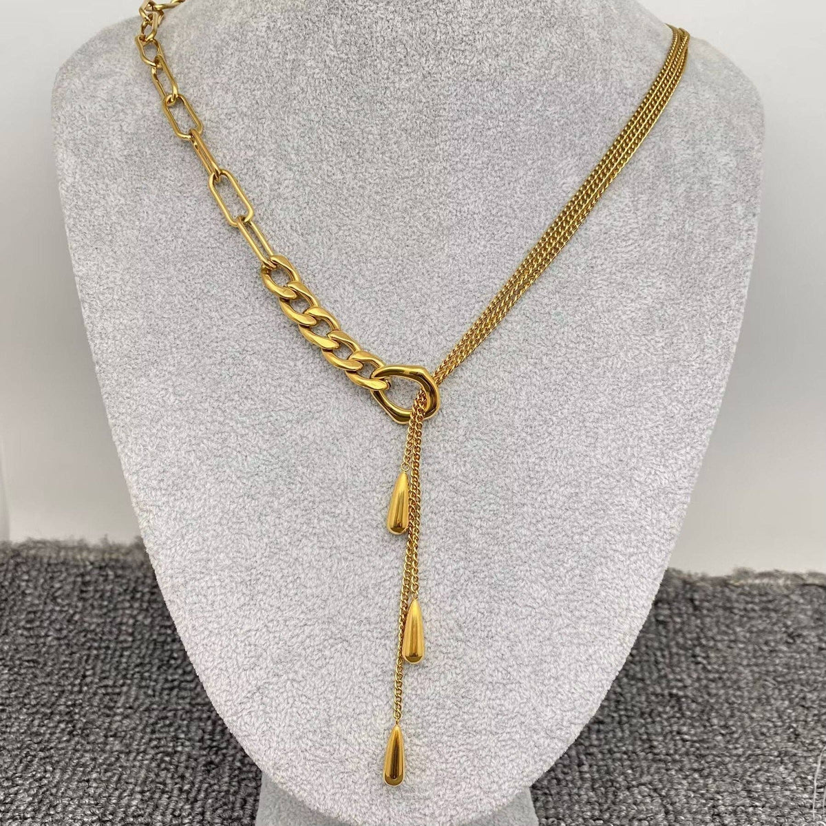 Gold chain necklace with teardrop charms on a gray mannequin bust
