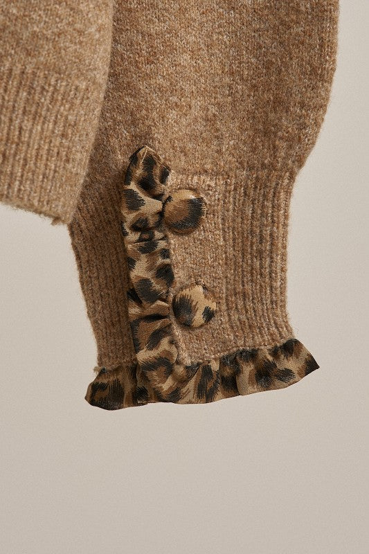Close-up of a brown knitted garment with leopard print cuffs on a beige background