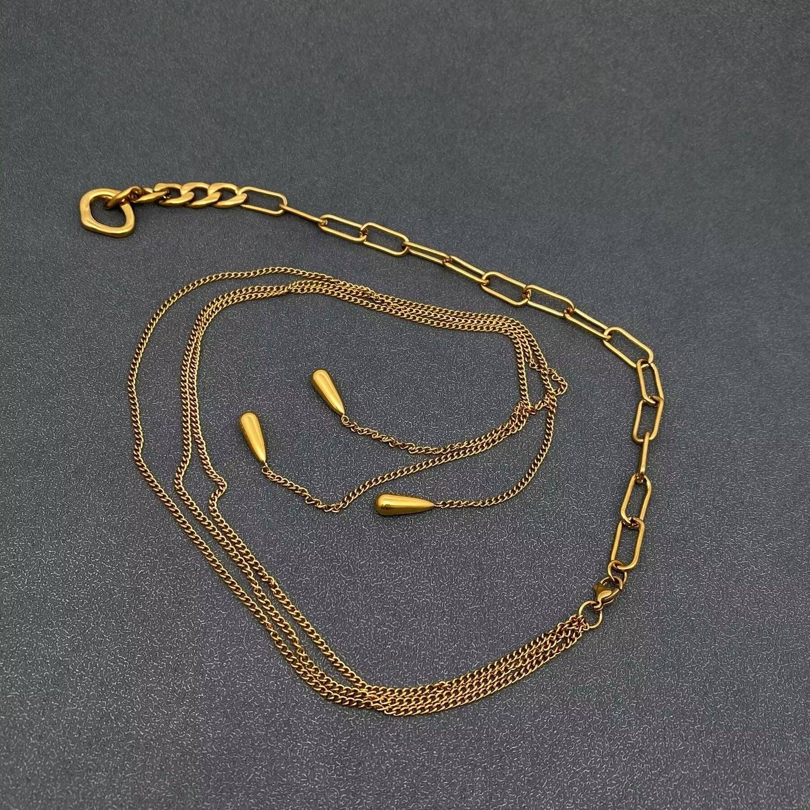 Gold chain necklace with teardrop charms on a gray mannequin bust