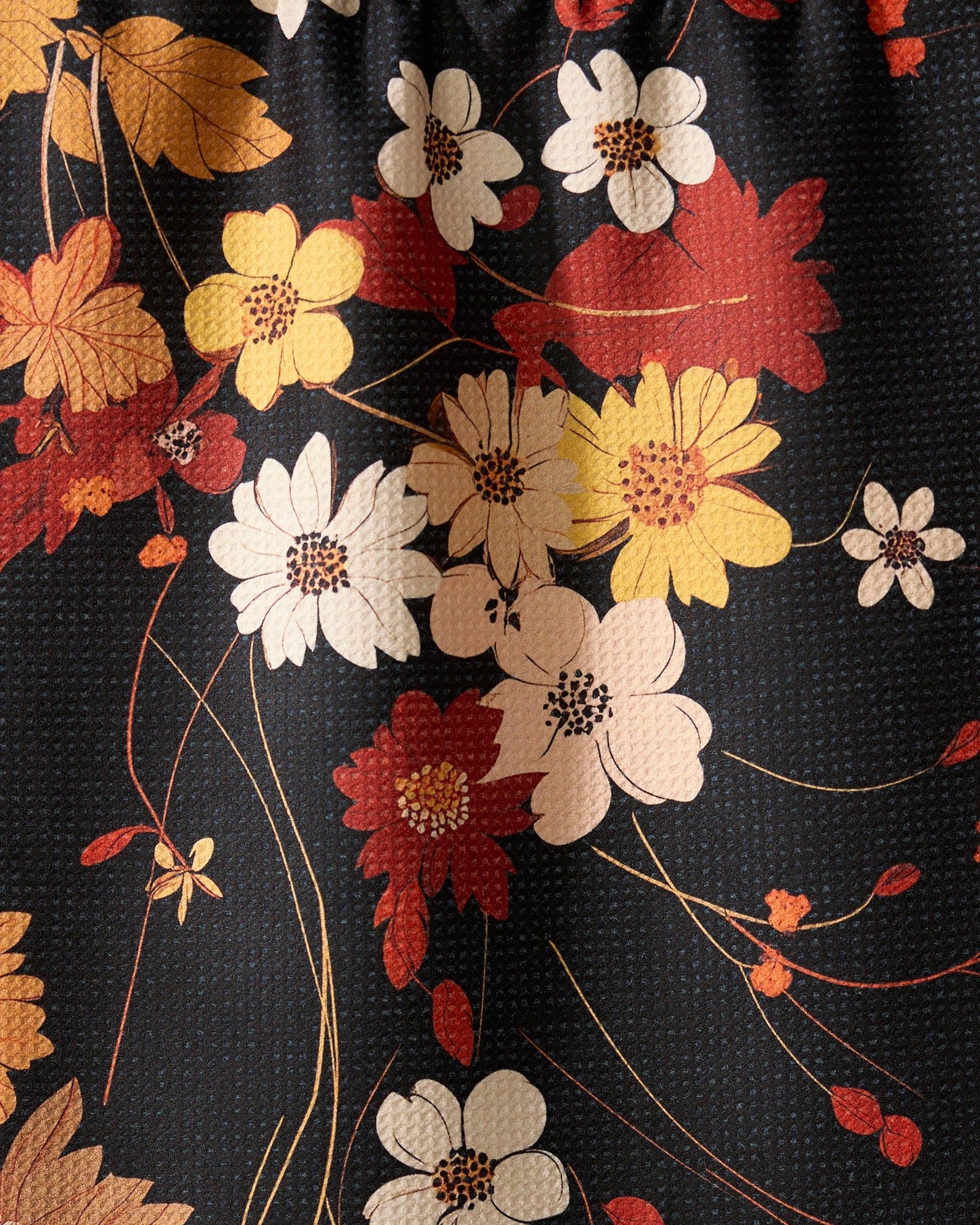 Floral-patterned tea towel on a string with apples and a bowl on a brown background